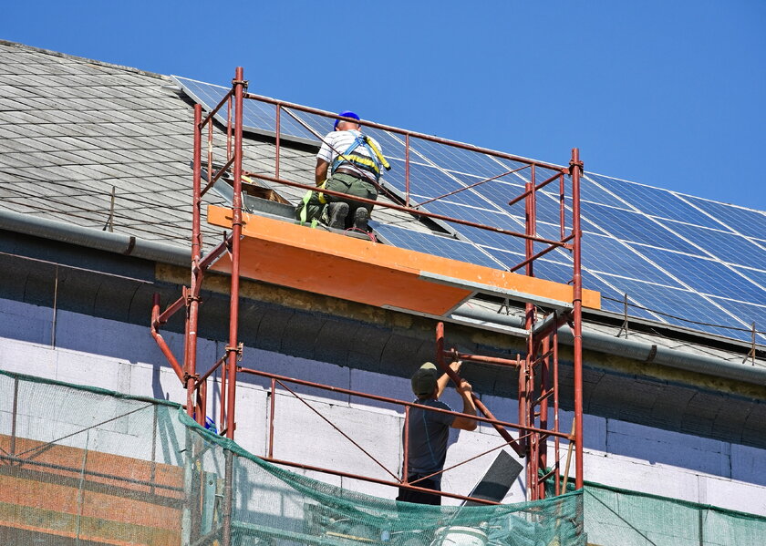 Baustelle mit Arbeitern an einer Solarkonstruktion auf Hausdach.