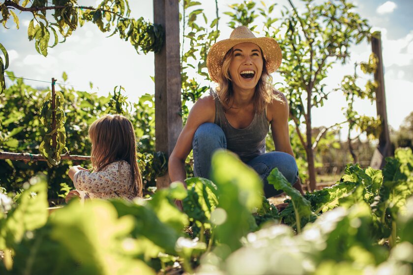 Bild Urban Farming Frau mit Kind in Gemuesebeet bei der Ernte.