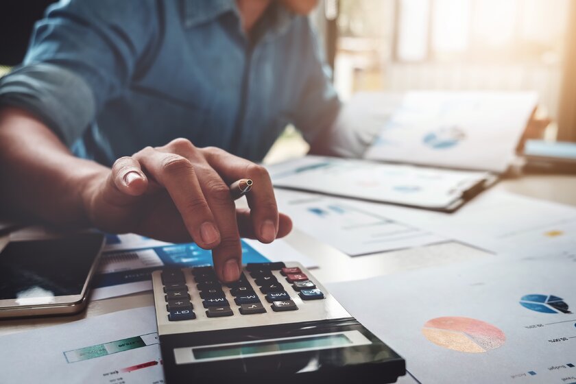 Bild Finanzplanung Mann im Homeoffice mit Taschenrechner, Dokumenten und Diagrammen bei der Finanzplanung.