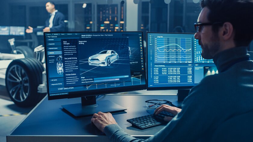 Ingenieur vor Computer mit 3D-CAD-Software und abgebildetem Elektroauto-Chassis-Prototyp.