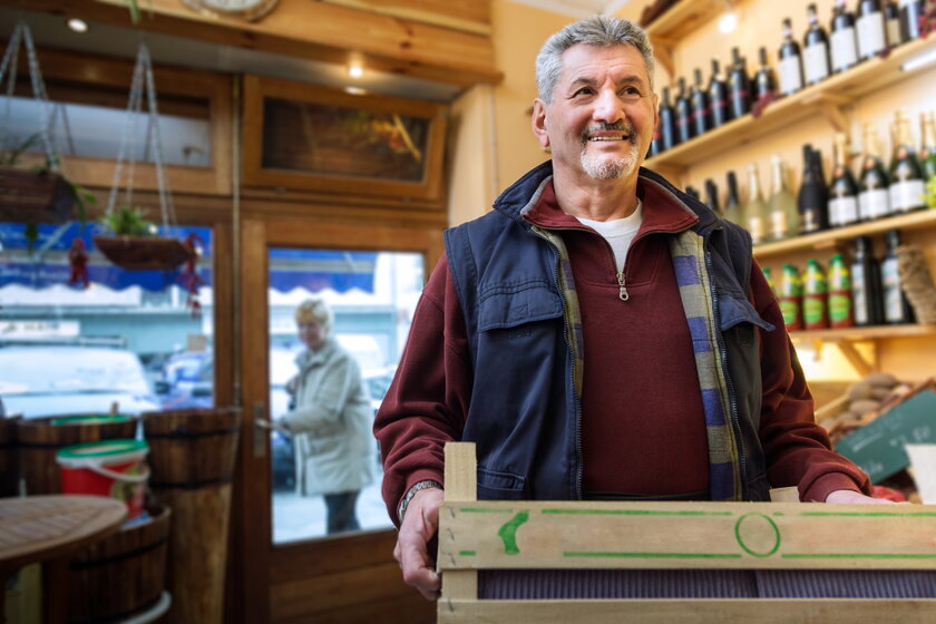 Bild Minijobber Freundlicher Mann mit Holzstiege arbeitet in kleinem Einzelhandel.