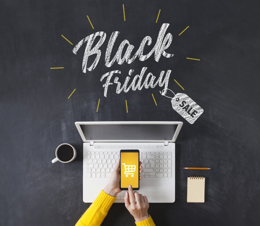 Black Friday Werbung auf einer Tafel und Blick von oben auf Frau beim Onlineshopping