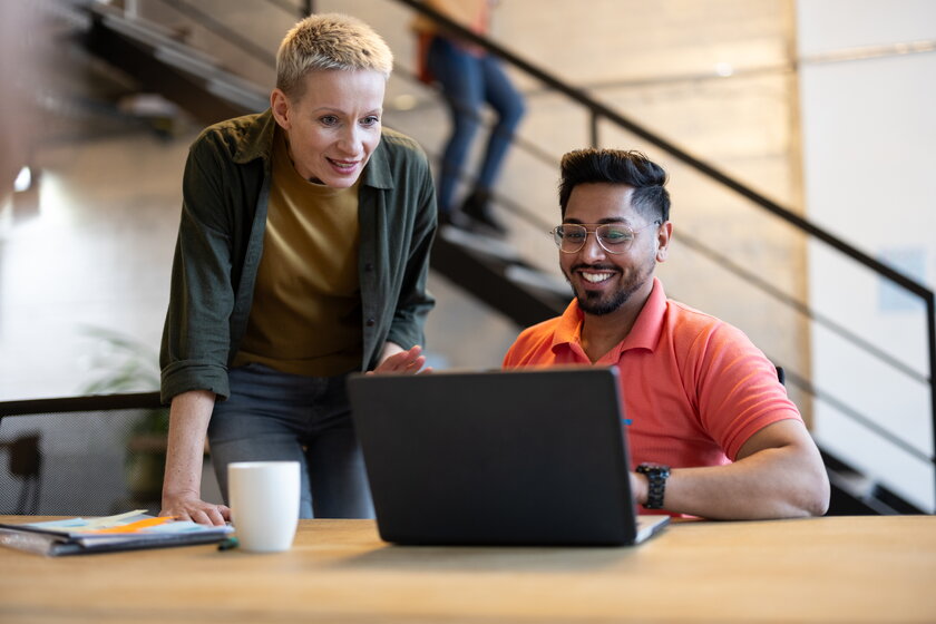 Bild Coworking Zwei Gruender, Mann und Frau arbeiten zusammen am Laptop in modernem Startup-Buero.