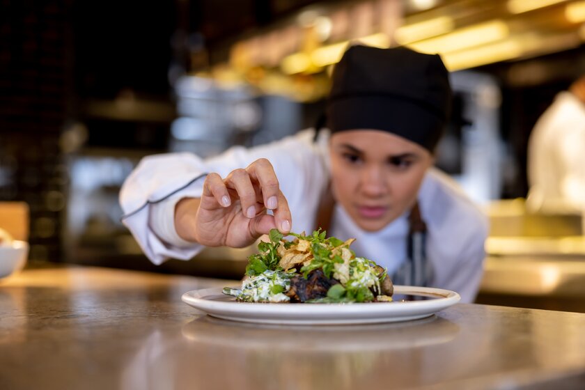 Köchin dekoriert sorgfältig einen Teller in der Küche eines Restaurants.