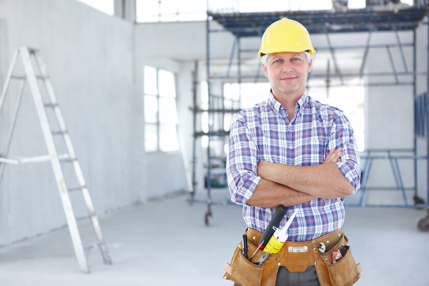 Bild Handwerksmeister Erfahrener Handwerksmeister mit Bauhelm auf seiner Baustelle blickt zuversichtlich in Kamera.