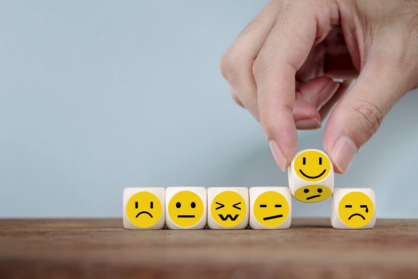 Eine Reihe von teils traurigen und teils fröhlichen Smiley-Spielsteinen symbolisiert das Konzept der Kundenzufriedenheit.