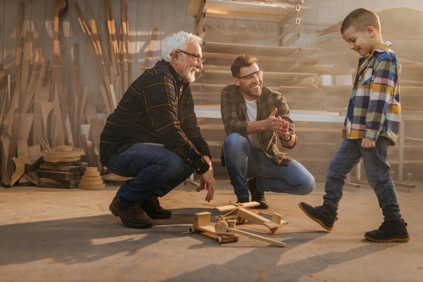 Drei Generationen einer Unternehmerfamilie im Tischlerhandwerk in einer Holzwerkstatt.