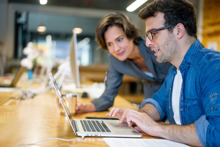 Mann und Frau als Gründerteam erstellen gemeinsam am Laptop einen Businessplan.