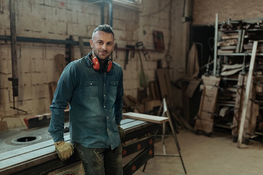 Bild DIY-Werkstatt Tischler lehnt an Arbeitsplatte in DIY-Werkstatt umgeben von Holz und Werkzeug.