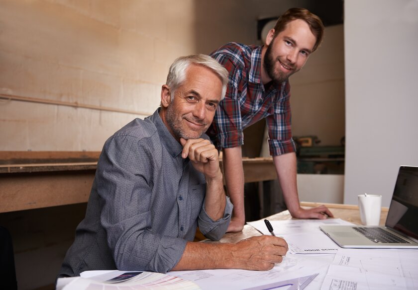 Vater und Sohn am Schreibtisch besprechen gemeinsame Projekte im Familienbetrieb.