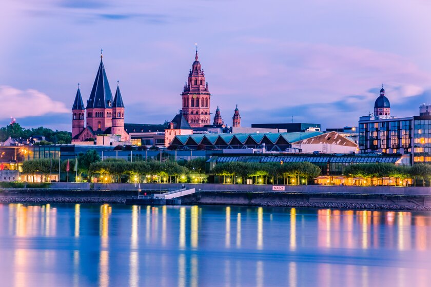 Mainzer Stadtkulisse mit Mainzer Dom spiegeln sich im Wasser des Rhein zur abendlichen Stunde.