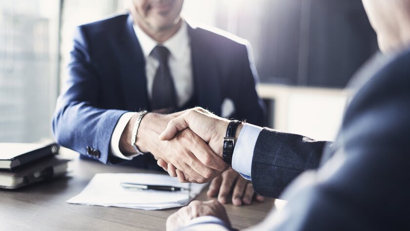 Unternehmer und Bankberater schütteln einander die Hand nach erfolgreichem Geschäftsabschluss.