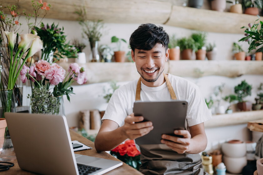 Kleinunternehmer in Blumenladen beim Online-Banking an seinem Tablet.