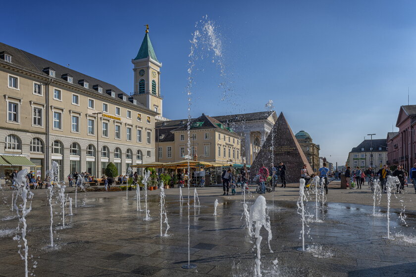 Blick auf den Karlsruher Marktplatz mit Brunnen und Pyramidenwahrzeichen.