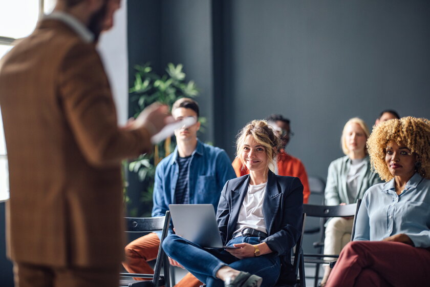 Mehrere Seminarteilnehmer gemischtgeschlechtlich sitzen in einem Workshop vor Referenten.