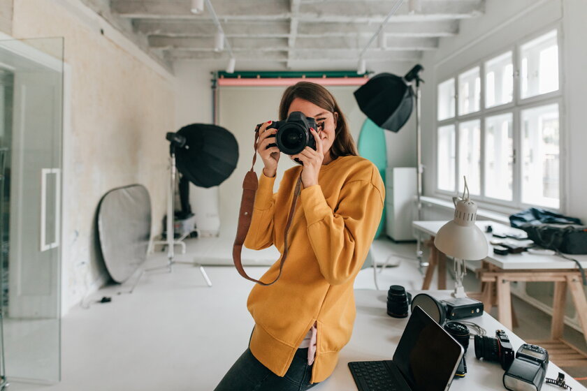 Fotografin mit Kamera in ihrem Atelier setzt zum frontalen Schnappschuss an.