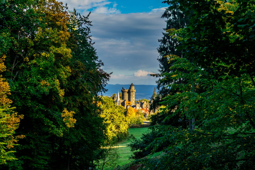 Blick durch den herbstlichen Wald im Bergpark Kassel mit Schloss Wilhelmshoehe.