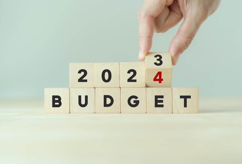 Hand dreht Holzwuerfel um und aendert die Aufschrift "BUDGET 2023" in "BUDGET 2024".