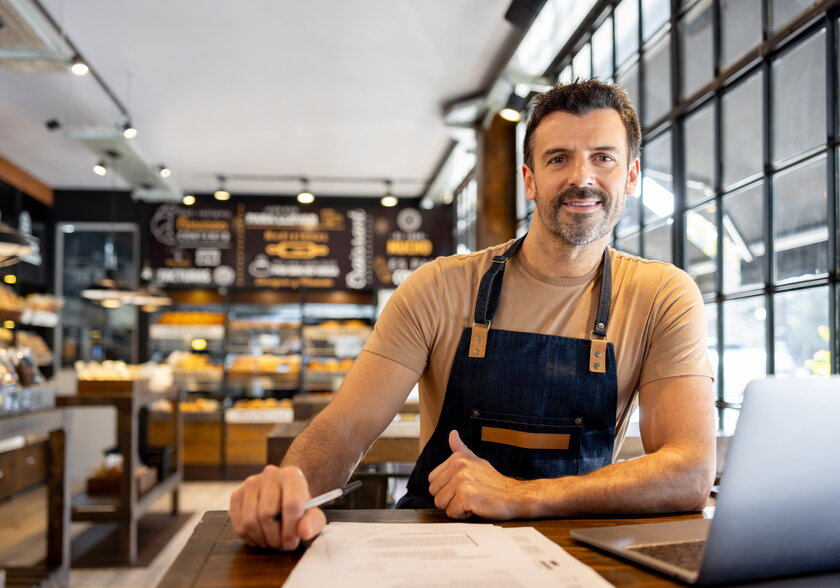 Unternehmer, der die Buchhaltung erledigt, während er in einem Café am Tresen lehnt.
