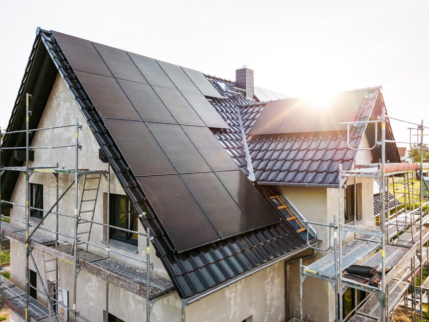 Bild Baustelle Einfamilienhaus Baustelle eines Einfamilienhauses mit Sonnenkollektoren im Morgenlicht.