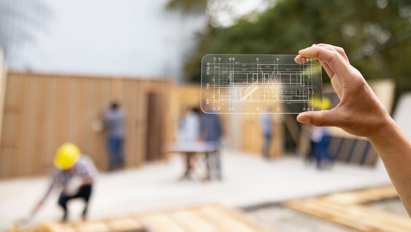 Architekt auf einer Baustelle betrachtet einen Bauplan mit einem interaktiven Bildschirm.