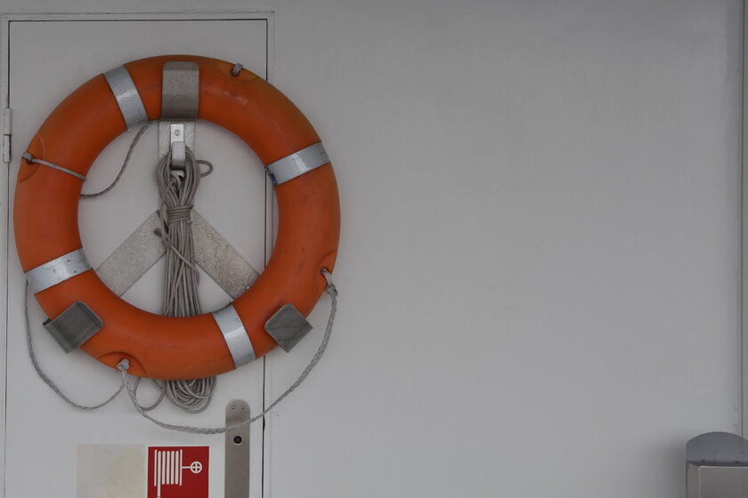 Rettungsboje mit Seil befestigt an Schiffswand.