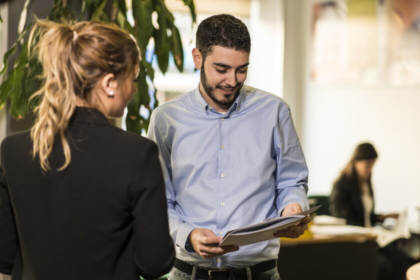 Sachbearbeiterin begutachtet Businessplan im Gespraech mit Gruender.