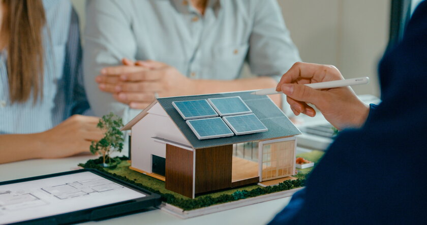 Bild Energieberatung Nahaufnahme einer Beratung zu Sonnenkollektoren anhand eines Modellhauses.