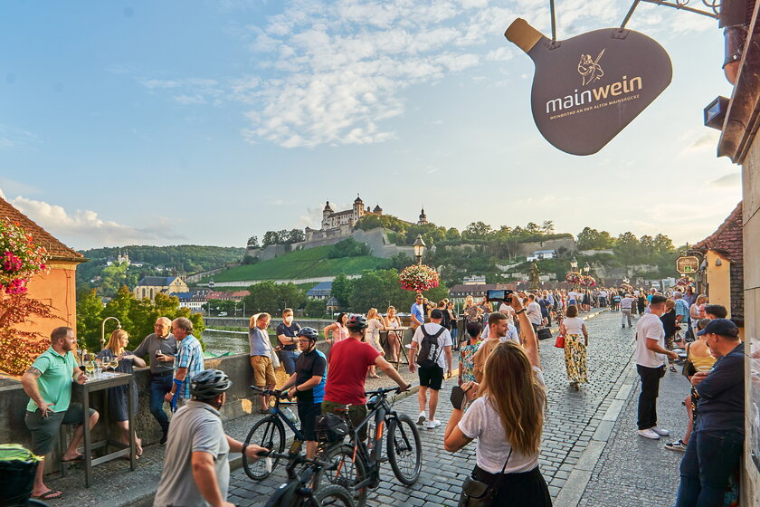 Fußgaenger und Radfahrer auf der alten Mainbruecke, im Hintergrund die Festung Marienberg.
