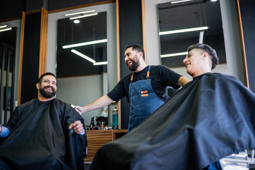 Barbier im Gespraech mit Kunden im Barber Shop.