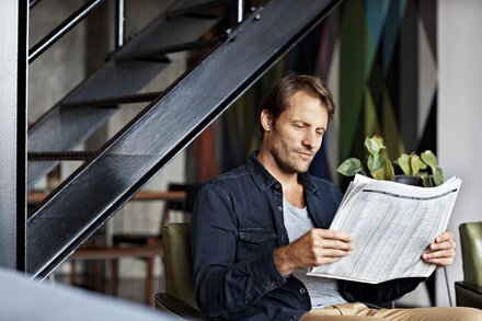 Unternehmernews der Woche 49/2016 Mann sitzt am Tisch und liest Zeitung