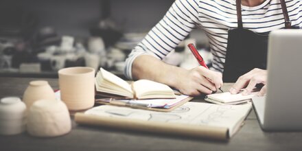 Handwerkerin am Schreibtisch mit Laptop und Papieren