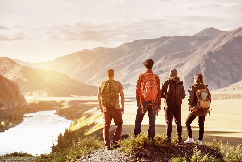 Bild Outdoor Wandern Gruppe von Menschen stehen auf einem Gipfel und blicken in weite Landschaft vor ihnen.