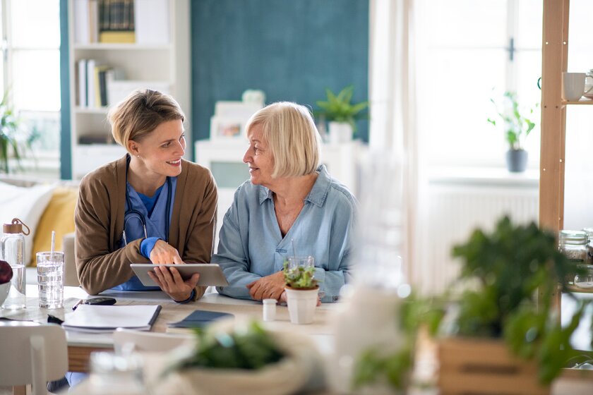 Examinierte Pflegefachkraft bespricht Medikation mit Seniorin.