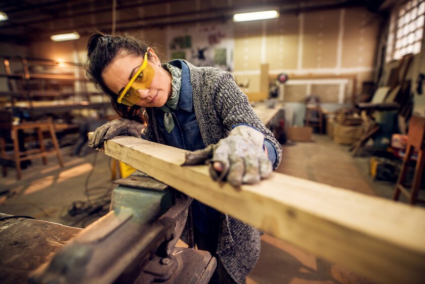 Bild Schreinerin Schreinerin in ihrer Werkstatt bearbeitet Holzbalken.