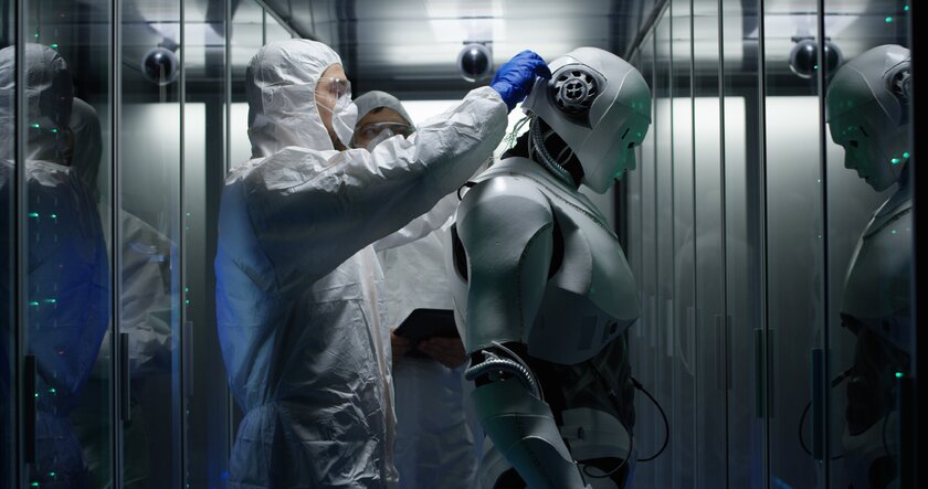 Mittlere Aufnahme von Ingenieuren, die Draehte an Robotersteuerungen befestigen.